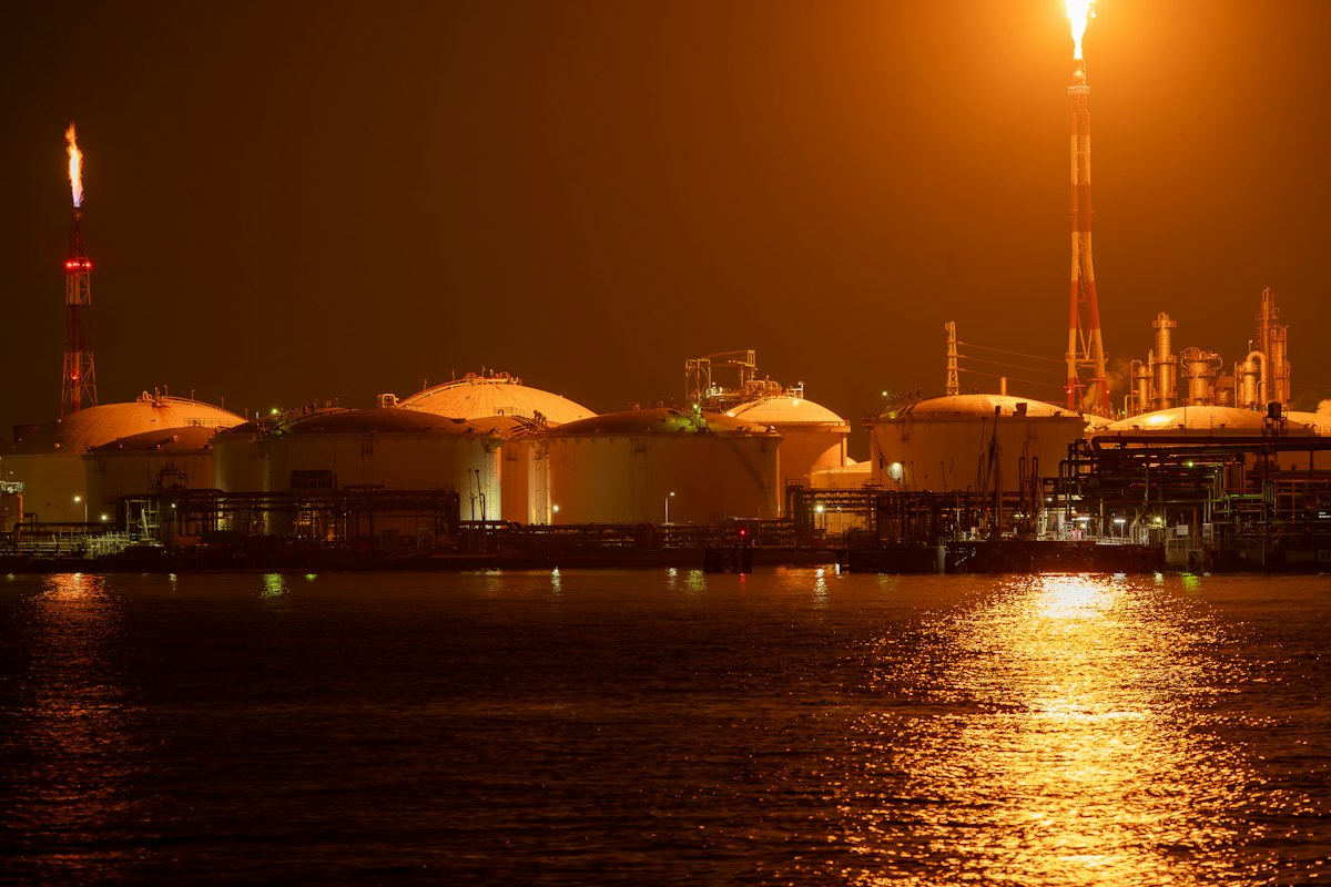 Reference photo: an illuminated refinery at night in Kawasaki, Japan; not the Nigerian assets in the TotalEnergies transaction.