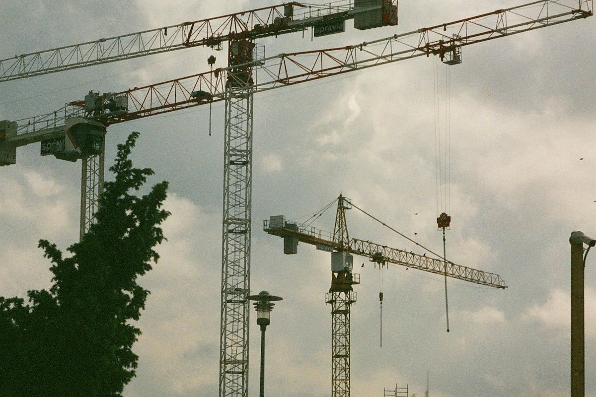 Industrial construction cranes and structures beneath a cloudy sky. Reference photograph, not a Nigerian investment project.